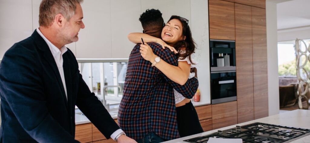 new home buyers hugging in new home kitchen with trusted buyers REALTOR by their side post NAR verdict.